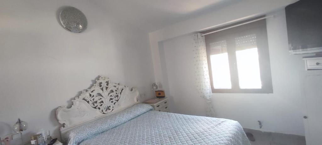 a white bedroom with a bed and a window at Mirador de Garciez in Torre del Campo