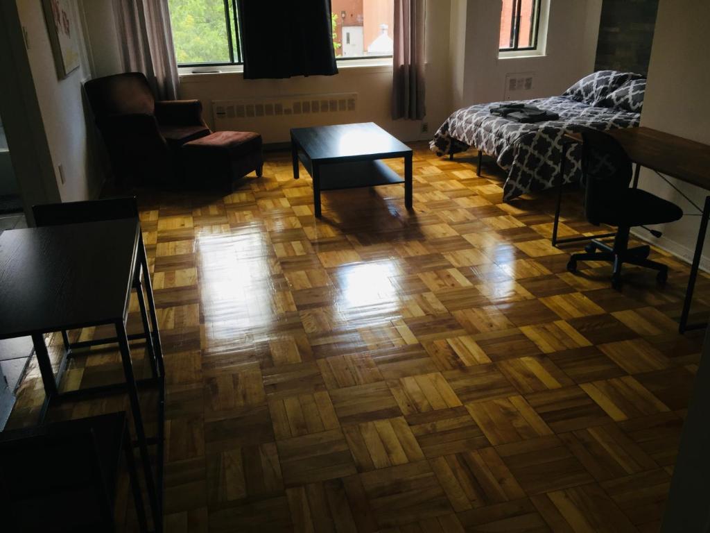 a living room with a wooden floor and a bed at Stylish Montreal Apartment: Comfortable Stay in the Golden Square Mile in Montreal