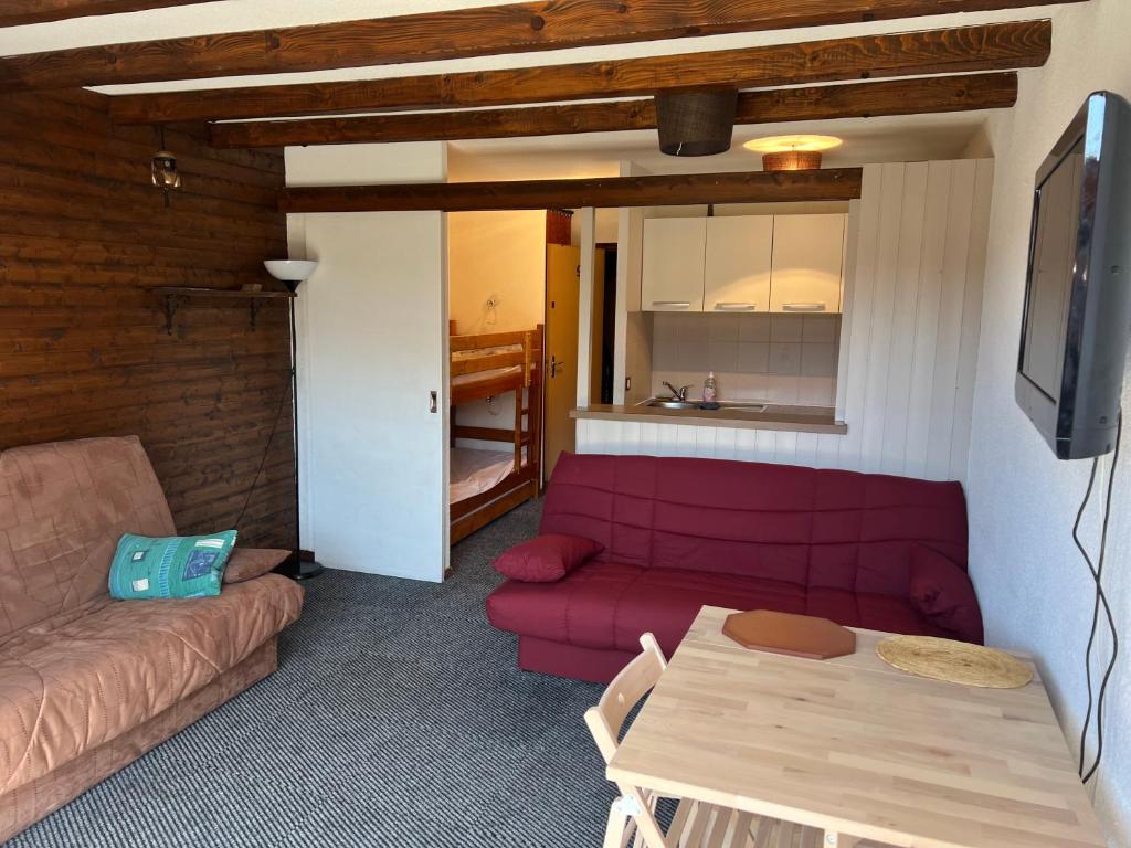 Orcières-Merlette le Panoramic في أورسيير: غرفة معيشة مع أريكة حمراء وطاولة