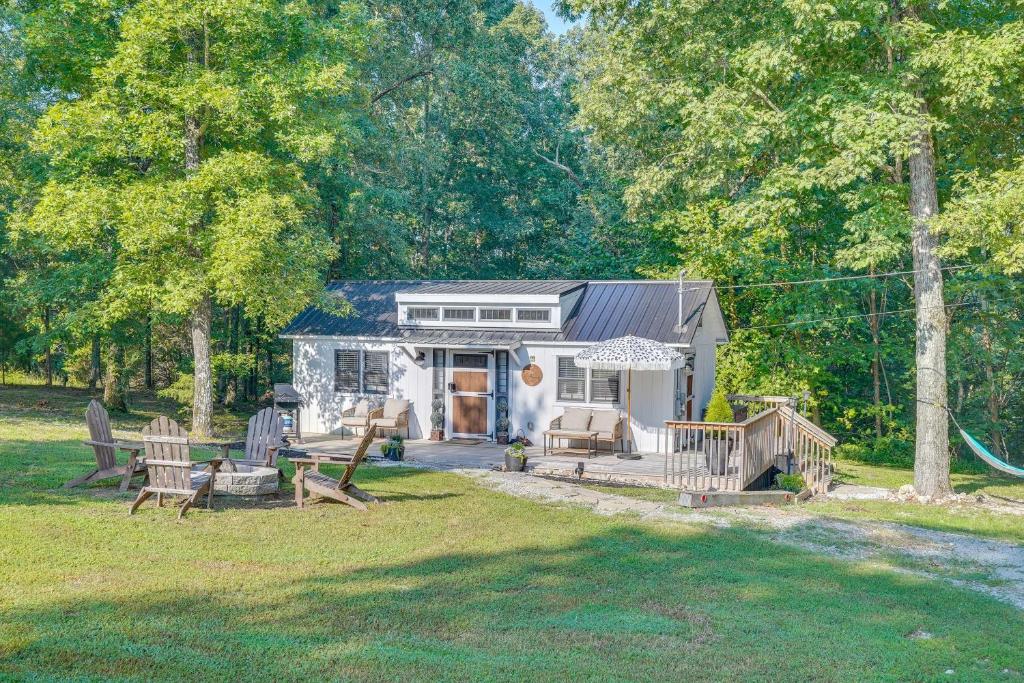 una pequeña casa blanca con sillas y un patio en Modern Camden Villa with Deck, Near Tennessee River, en New Johnsonville