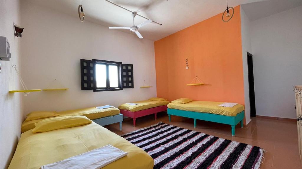 a room with three beds and a rug at Deep South Hostel in Marsa Alam City