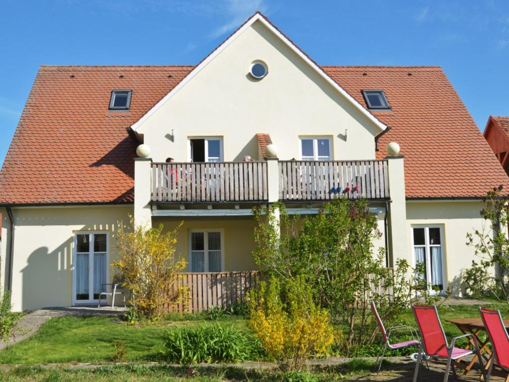 een huis met een balkon en rode stoelen bij Pfauenauge in Colmberg