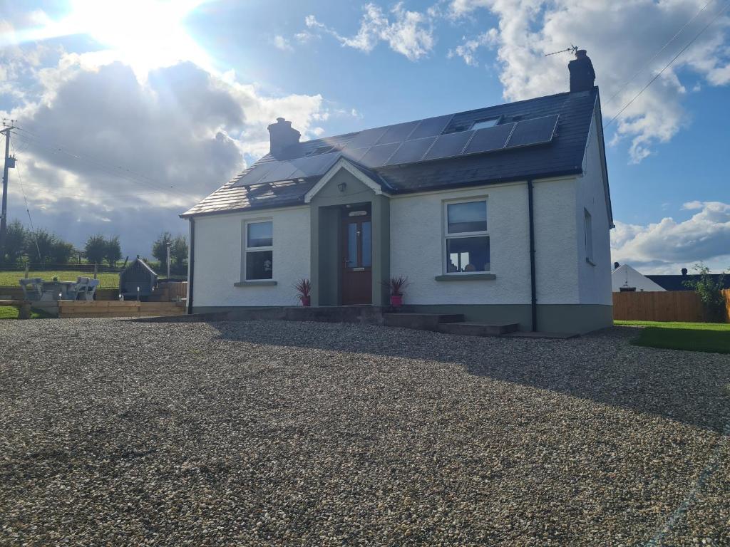 Casa blanca con paneles solares en el techo en Kingarrow Cottage en Omagh