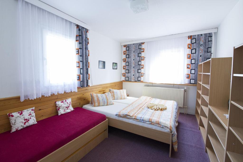 a bedroom with two beds and two windows at Rodinný penzion Skiland in Ostružná