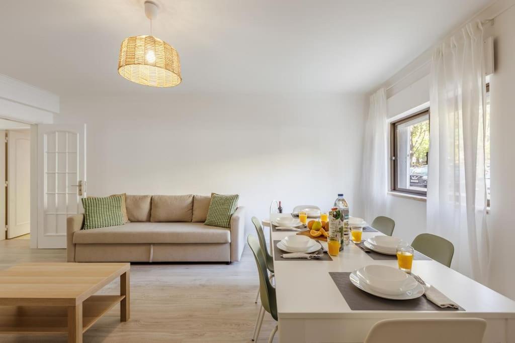 a white living room with a table and a couch at Massamá 26 / free park on premises/ smart TV in Queluz