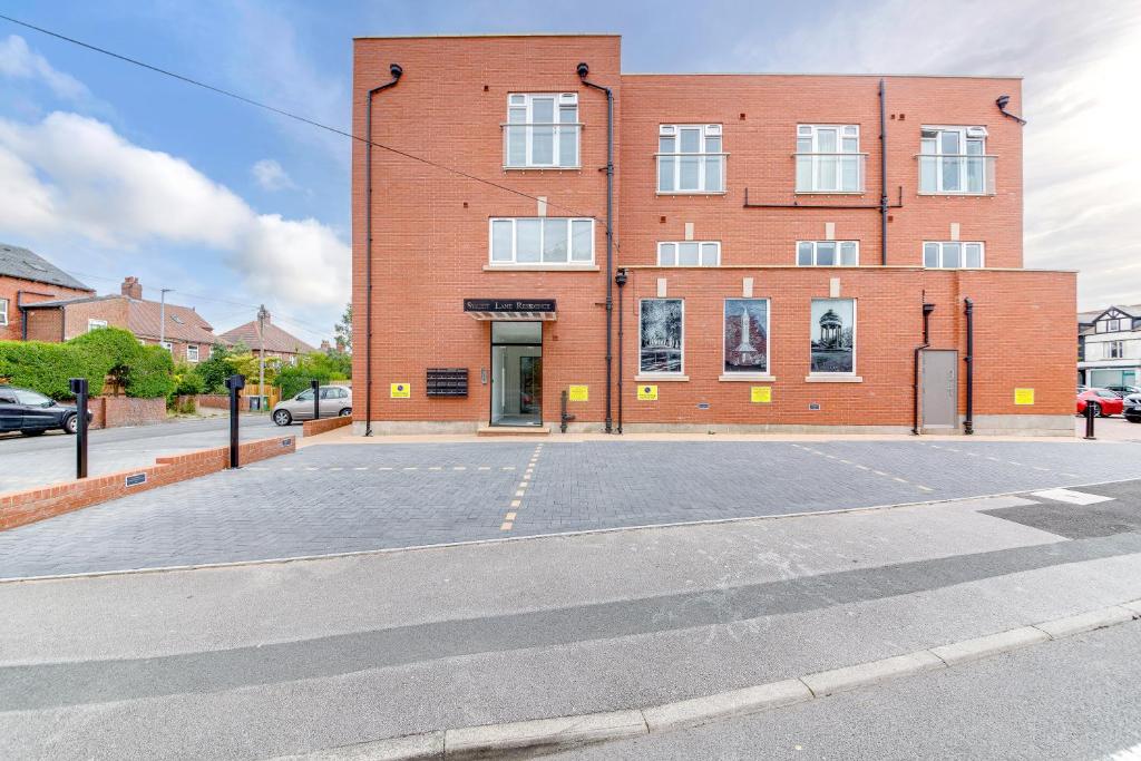 an empty parking lot in front of a brick building at Superior Compact Studio Close to Amenities in Leeds