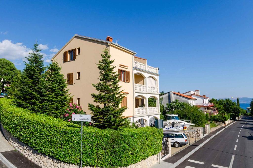 a building with a hedge in front of a street at Two-Bedroom Apartment Crikvenica 19 in Dramalj