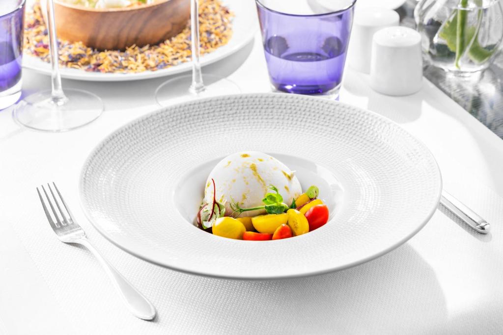 a white plate with ice cream and vegetables on a table at Palácio Estoril Hotel, Golf & Wellness in Cascais