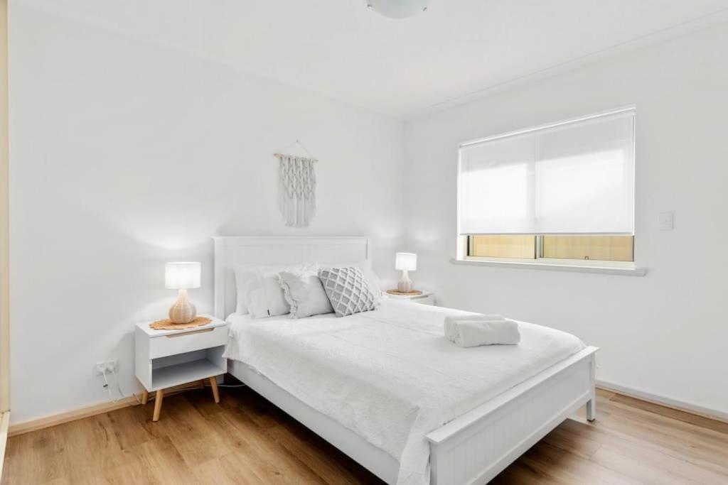 a white bedroom with a large bed and two lamps at Seymour Cottage in Victor Harbour in Victor Harbor
