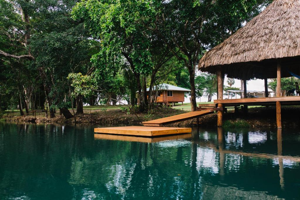 una piscina de agua con un edificio y una cabaña en Crystal Creek Lodge, en Orange Walk