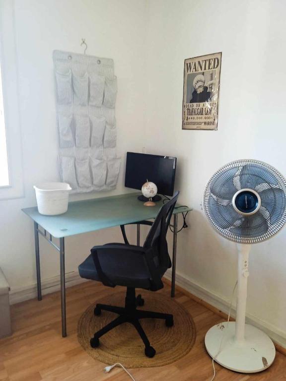 a desk with a fan and a desk with a chair at Chambre cosy chez Schéhérazade in Toulon