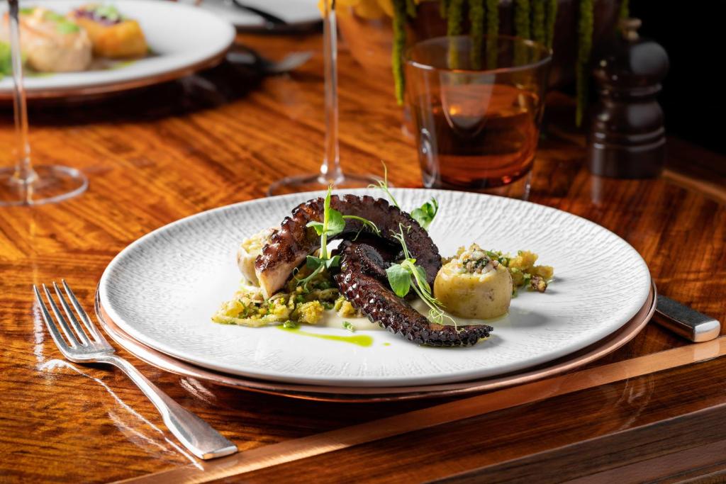 a white plate of food on a wooden table at Palácio Estoril Hotel, Golf & Wellness in Cascais