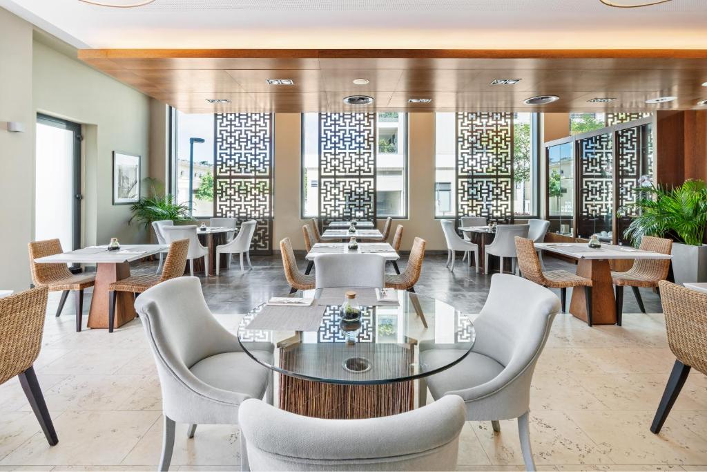a dining room with tables and chairs and windows at Palácio Estoril Hotel, Golf & Wellness in Cascais