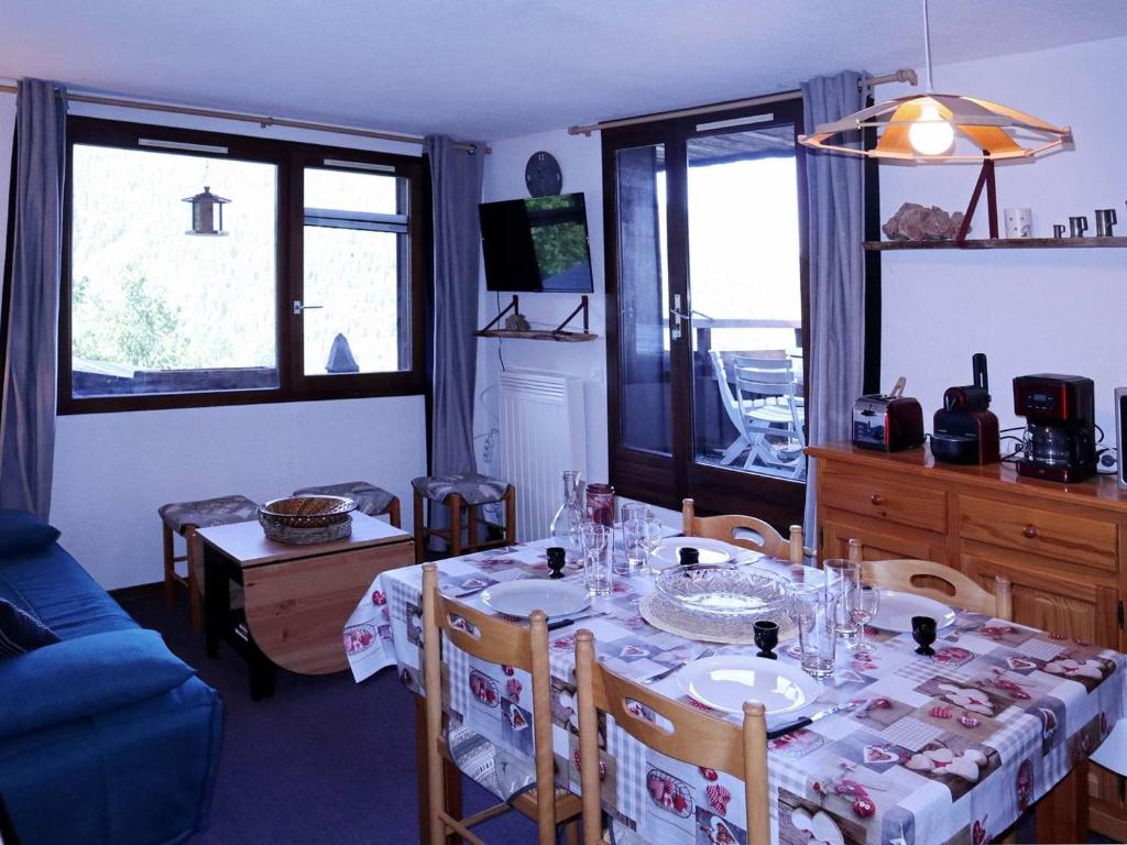 a dining room with a table and a blue couch at Appartement Les Orres, 3 pièces, 6 personnes - FR-1-322-532 in Les Orres