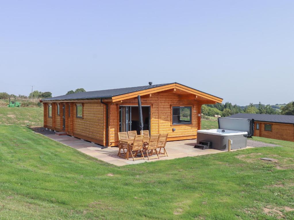 a log cabin with a grill and chairs on a patio at Foxglove Lodge in Exeter