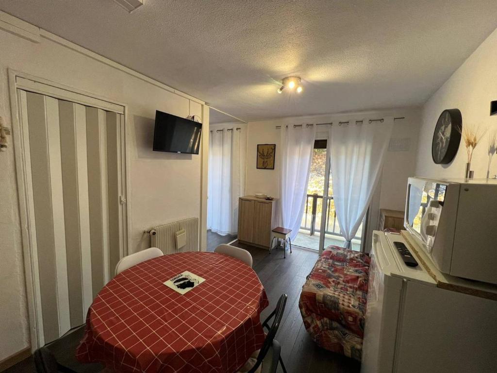 een kamer met een rode tafel en een kamer met een bed bij Studio Les Angles, 1 pièce, 4 personnes - FR-1-593-92 in Les Angles