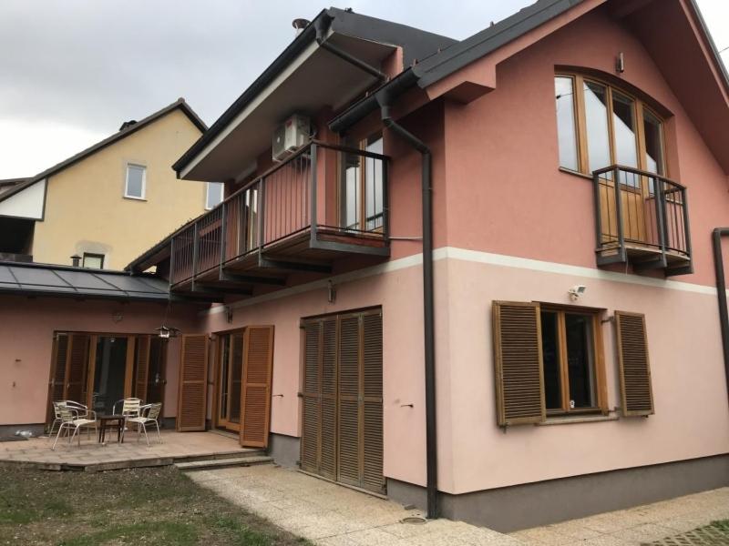 een roze huis met een balkon en een tafel bij Buzahouse in Ljubljana