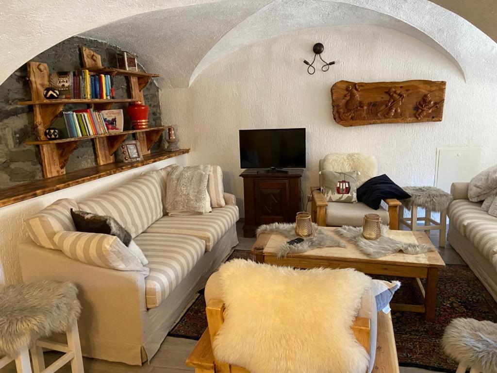 un soggiorno con divani bianchi e TV di Les Chemines a La Thuile