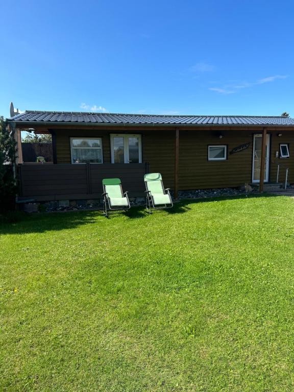 two chairs sitting in a yard in front of a house at Fischerhütte III Mobilheim in Polchow