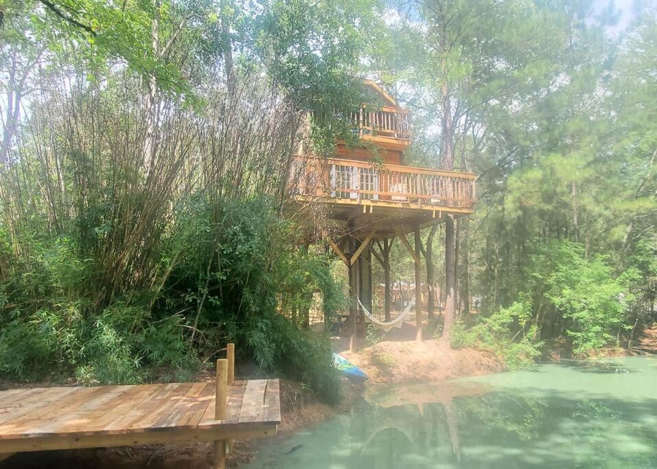 a tree house with a deck over a body of water at Waterfront Treehouse in a Magical Forest in Waller