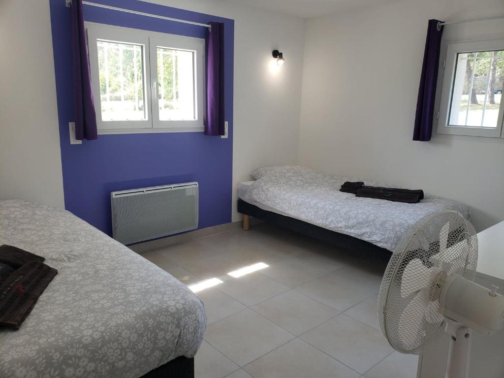 a room with two beds and a fan and two windows at Le gîte du temps suspendu in Anduze