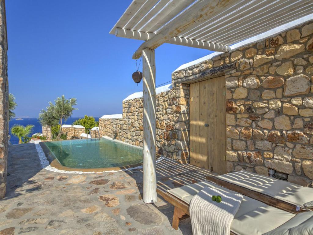a stone walled pool with a bench and an umbrella at Eirini Luxury Hotel Villas in Grikos