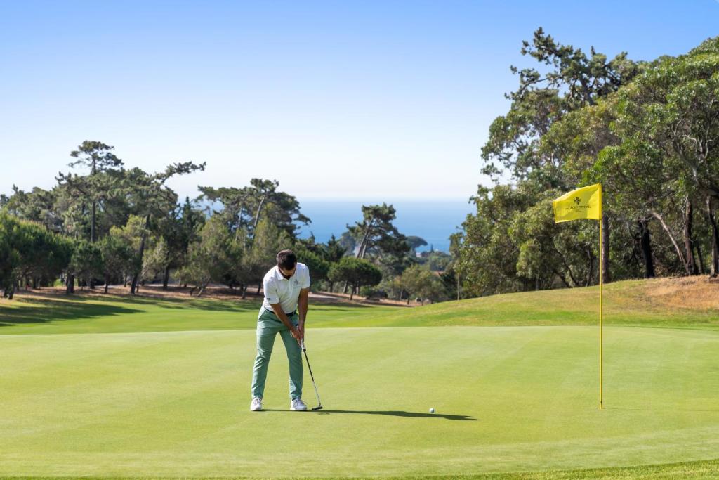 a man is playing golf on a golf course at Palácio Estoril Hotel, Golf & Wellness in Cascais
