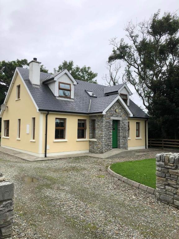 una casa amarilla con techo negro en 2 Ballyloskey Road en Carndonagh