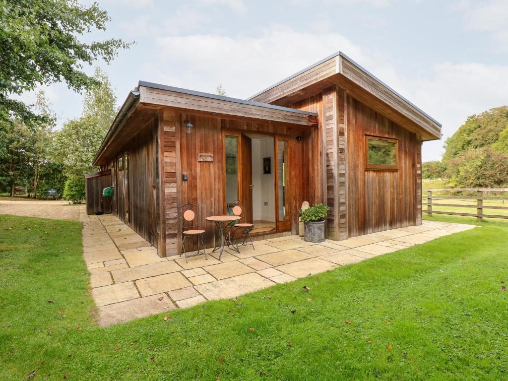 a wooden cabin with a table and chairs in a field at Hambleton in Cottesmore