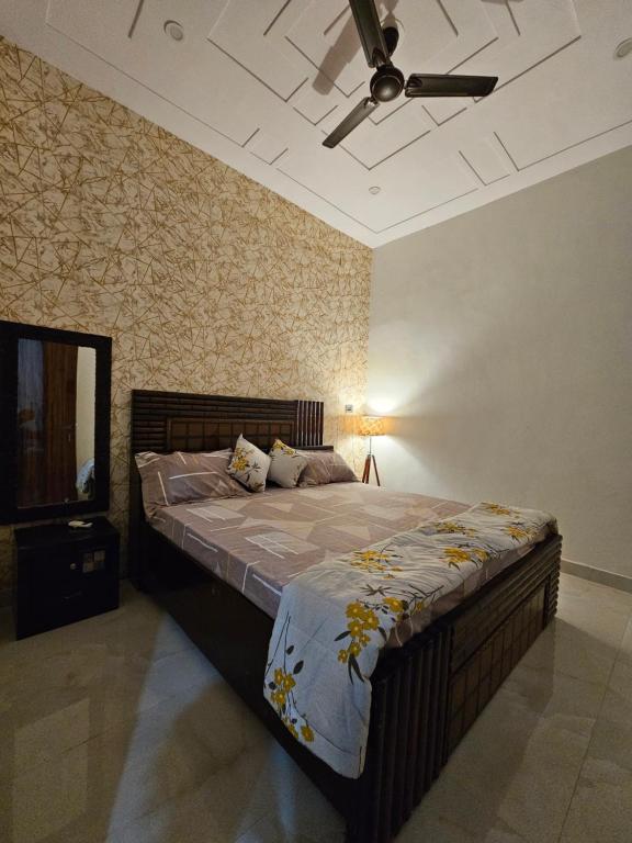 a bedroom with a large bed and a ceiling fan at Nirmal sadan Homestay in Kāman