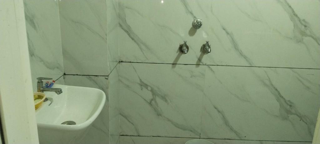baño con lavabo y pared de mármol blanco en Hotel shree Gajanand palace, en Ujjain