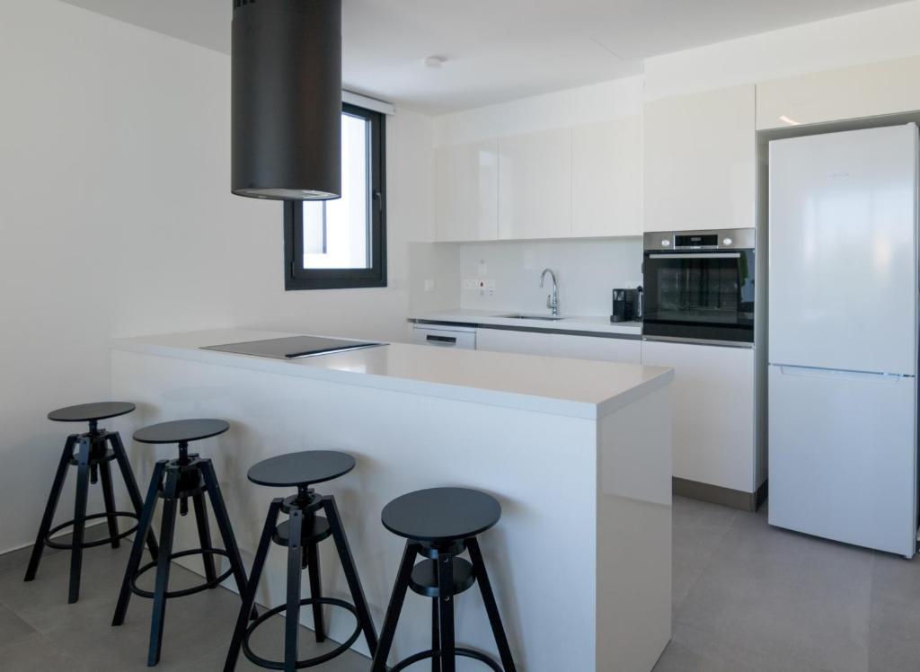uma cozinha com um balcão branco com bancos à volta em Phaedrus Living White Hills Suites Panoramic View em Aglantzia