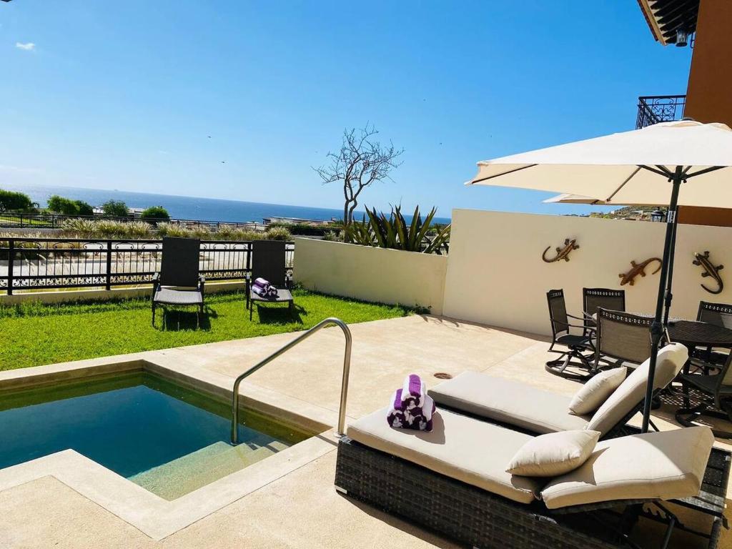 a swimming pool with an umbrella and some chairs at Casa Paradiso Copala Private Home in Quivira Community in Cabo San Lucas