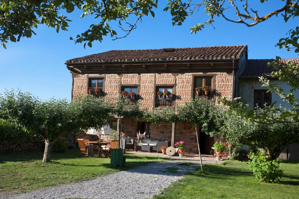 una antigua casa de ladrillo con jardín y árboles en Hotel Rural La Aceña en Quintanaluengos