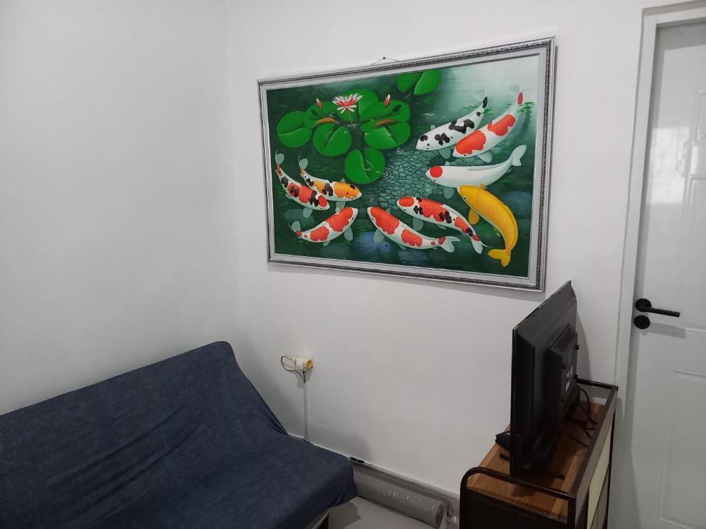 Habitación con una pintura en la pared y TV. en Villa Akela Sukabumi en Sukabumi