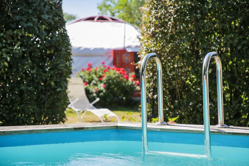 a swimming pool with two metal bars in a yard at Yourte au Paradis in Souvigné