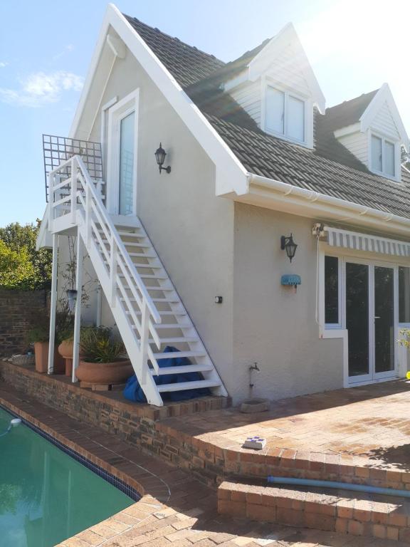 a white house with a staircase next to a pool at Karsen residence in Cape Town