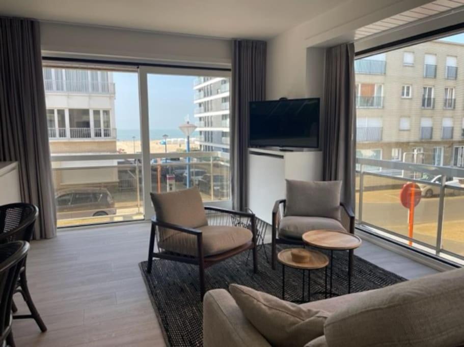 un salon avec un canapé et des chaises et une grande fenêtre dans l'établissement Dzee Appartement frontaal zeezicht en gratis parking, à Coxyde