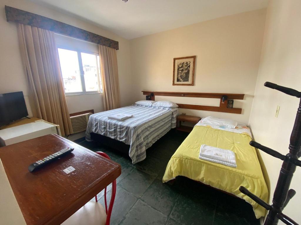 Cette petite chambre comprend deux lits et une table. dans l'établissement Suíte no centro de Angra dos Reis - 13, à Angra dos Reis