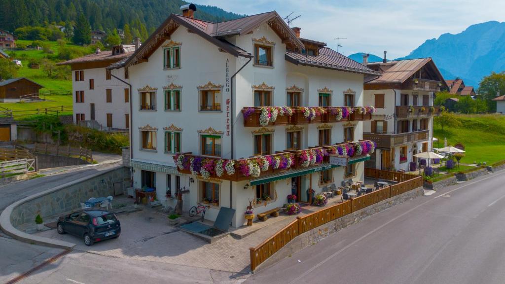 a large white building with flowers on the side of it at Albergo Serena in Auronzo di Cadore