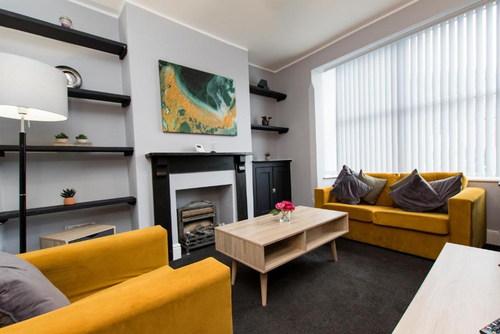 a living room with yellow couches and a fireplace at Newly Renovated Perfect Family Home in Nottingham in Nottingham