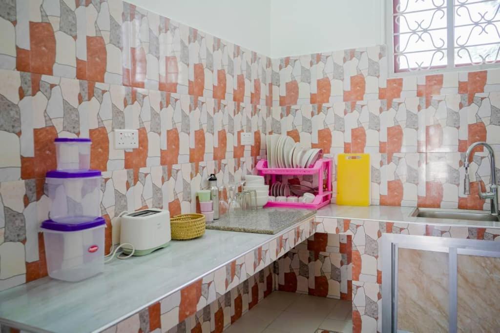 a kitchen with a counter with a sink and tiles at MOYOWANGU HOUSE PAJE in Paje