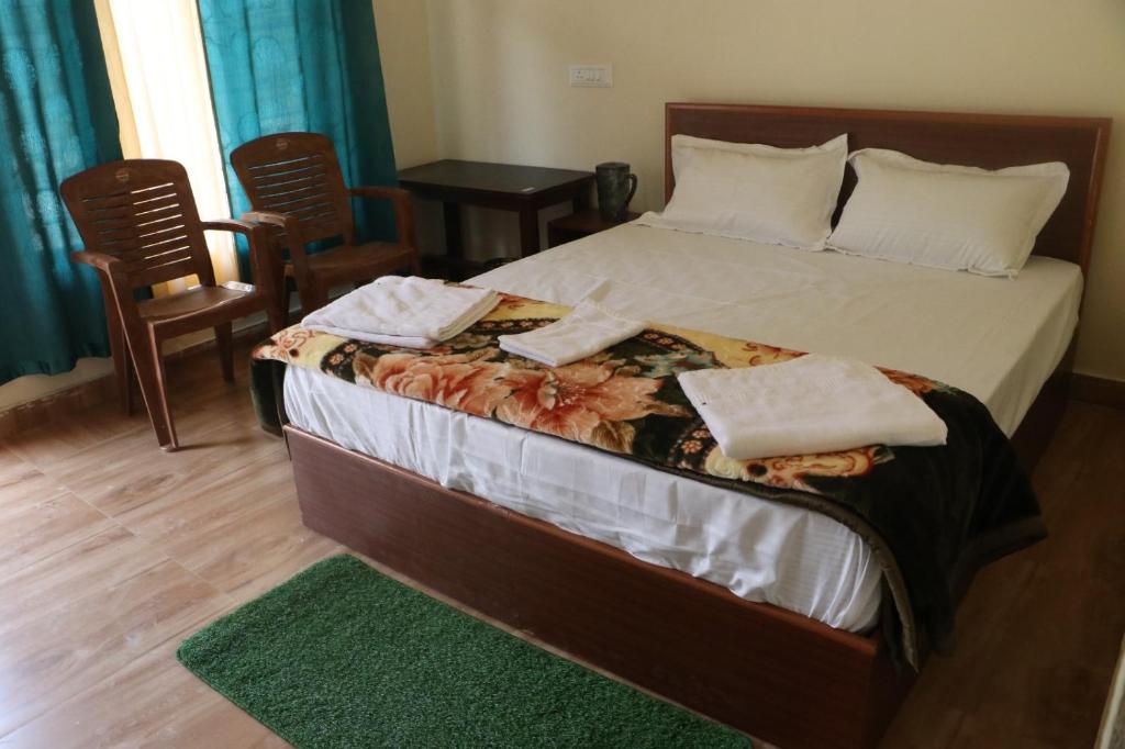 a bedroom with a bed with two towels on it at Kalika Hill Resort in Barkot