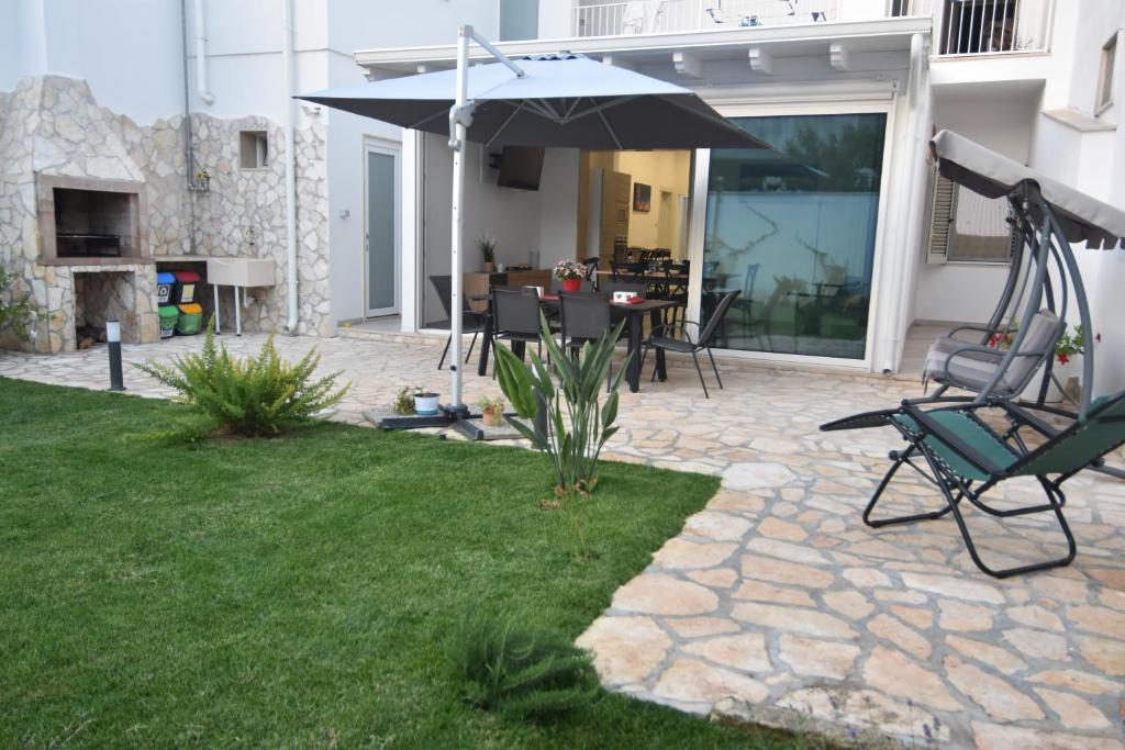 eine Terrasse mit einem Sonnenschirm, Stühlen und einem Tisch in der Unterkunft Casa Romeo in Lecce