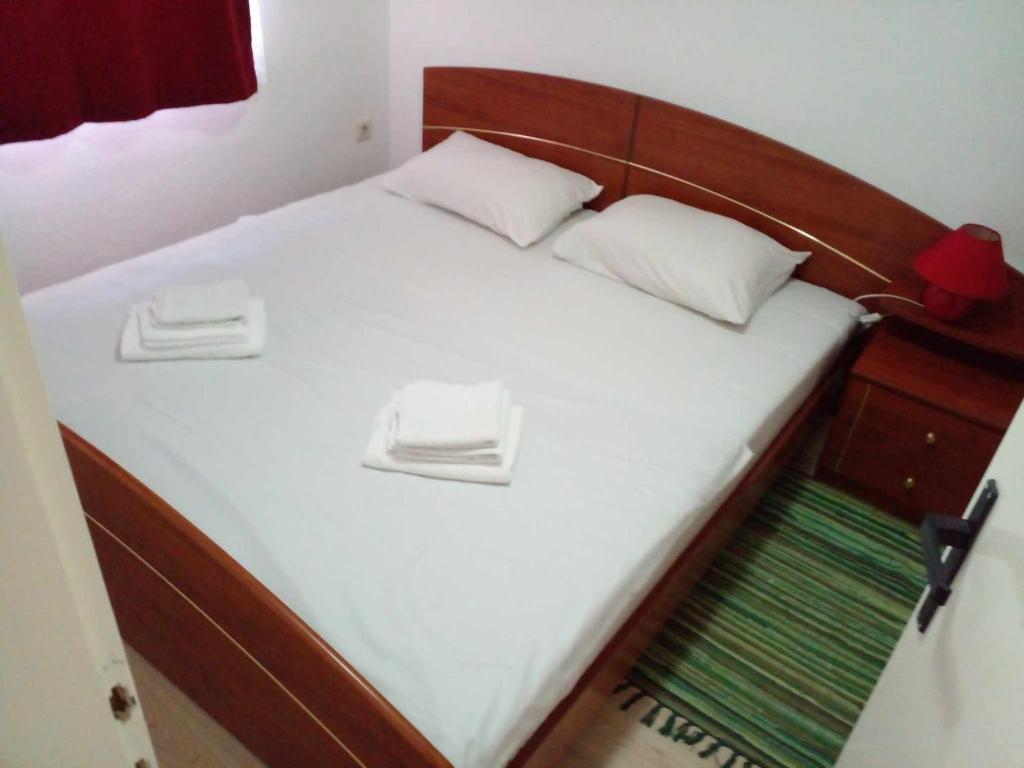 a bed with white sheets and white pillows on it at Stan na dan Apartman Kozarac in Kozarac