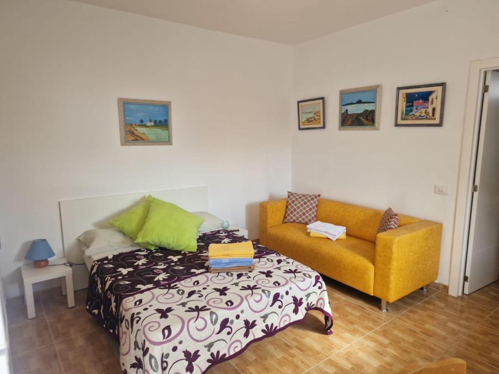 a bedroom with a bed and a yellow couch at Casa Carmen in Castillo del Romeral