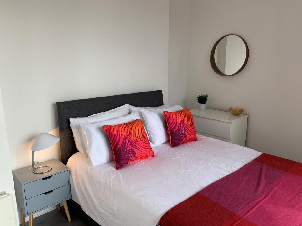 a bedroom with a bed with two red pillows at Chertsey - Beautiful Modern 2 Bedroom Apartment in Chertsey