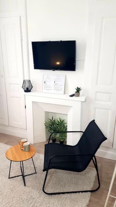 - un salon avec une chaise noire et une télévision dans l'établissement Le Chat Bleu - 26m2- Terrasse sur les toits - Wi-fi, à Amiens