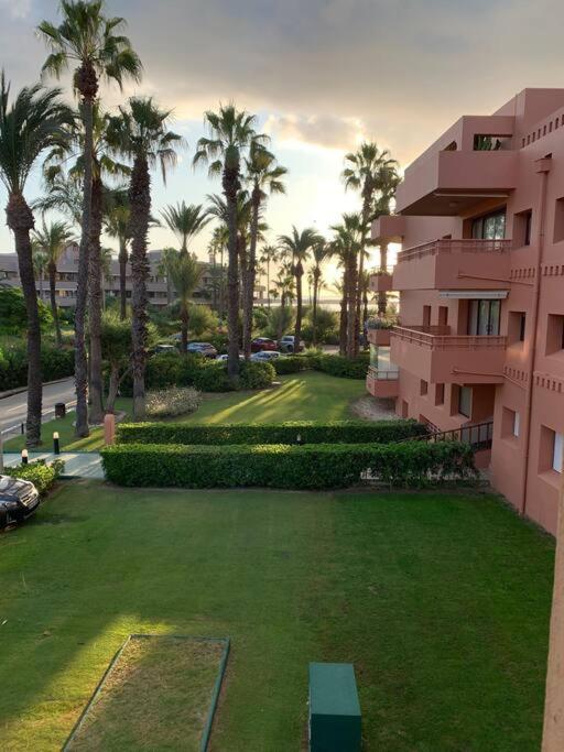 a view of a building with palm trees and a yard at Charming 3 Bedroom apartment with sea view in the heart of Sotogrande in Sotogrande