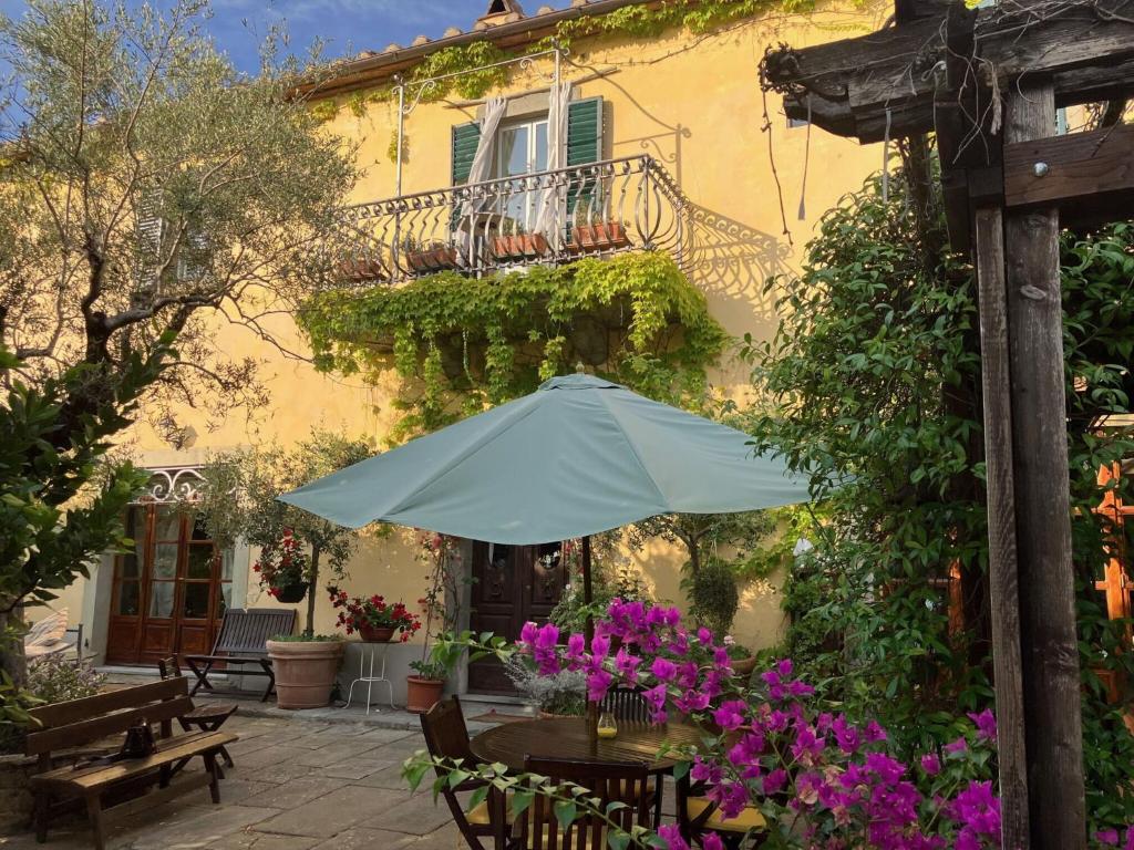 een patio met een tafel met een parasol en bloemen bij Villa Toppani Del Sodo in Cortona